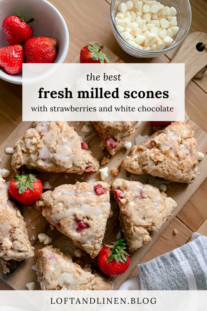 fresh milled white chocolate strawberry scones on a wooden cutting board on a wooden table formatted for a pinterest pin