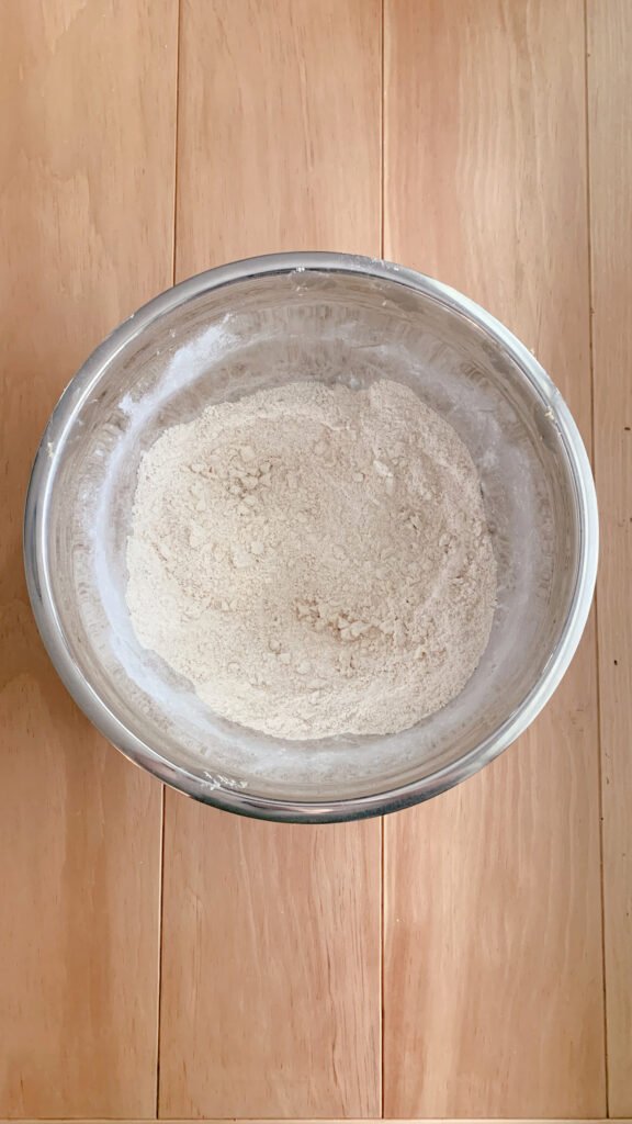 a stainless steel bowl of dry ingredients and cubed butter cut in for fresh milled white chocolate strawberry scones on a wooden table