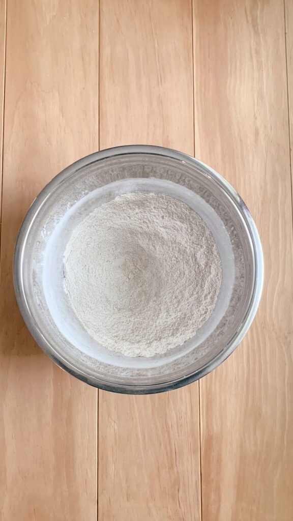 a stainless steel bowl of dry ingredients for fresh milled white chocolate strawberry scones on a wooden table